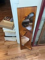 Front view of solid wood wall mirror showing mirror insets and two triangular shelves