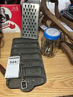 All items together: cast iron mold, box grater, jar of openers, peeler visible
