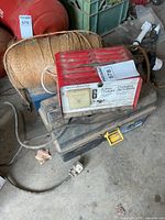 Battery charger, spool of twine, plastic toolbox and metal toolbox visible together