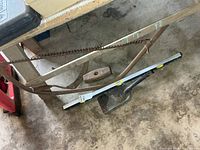 Overview of bow saw, sledge hammer head, level and shovel on floor