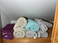 Rolled bath towels and folded purple towels on shelf