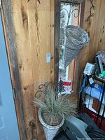 Pair of wall brackets with attached wicker cone planters, one containing faux plant
