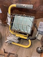 Front view of yellow halogen work light with wire guard and coiled cord