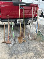 Full group of eight long-handle yard tools leaning against truck tailgate