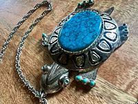 Front view of turtle pendant necklace showing faux-turquoise cabochon and bead accents.