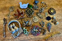 Overhead view of entire assortment of brooches, pendants pins and charms on wooden surface