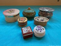 All seven decorative boxes arranged on blue cloth