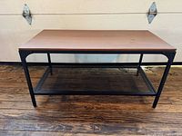 Front three-quarter view showing full table, wood top, metal frame and mesh shelf