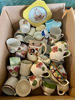 Overview of entire box contents showing variety of cups and plate on top