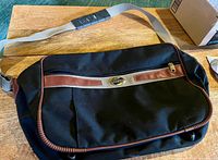 Front view showing bag shape, strap and wheels