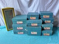 Stack of turquoise Madame Alexander boxes with one yellow window box at left