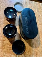 Both lenses, two caps and Petri zip case displayed