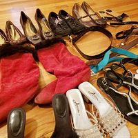 Overview of assorted shoes, boots and belts laid out on wood floor