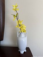 Full view of white urn vase with faux yellow flowers