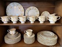 Two-shelf cabinet view showing majority of dinnerware pieces including plates, teacups and creamer