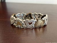 Front view of stretch bracelet showing tri-tone heart links and engraved message
