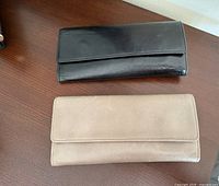 Two wallets closed showing black and taupe exteriors
