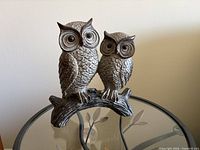 Front view of resin double-owl figurine on glass table