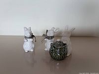 Front view of three white ceramic bunny figurine shakers and green leaf pot