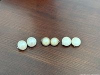 All three pairs of round faux pearl clip-on earrings laid out side by side