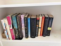 Entire row of 15 hardcover books on white shelf