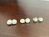 Three pairs of faux pearl earrings laid out side by side