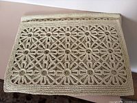 Stack of beige crocheted placemats displaying thickness and pattern