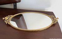 Full view of oval gold filigree mirror tray on tabletop