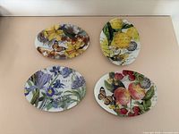 All four oval plates laid out showing different fruit and floral designs