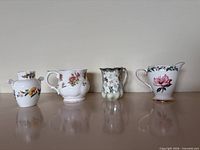 Front view of all four porcelain creamers lined up