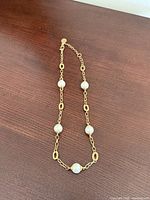 Full view of necklace laid out showing chain style and five faux pearls