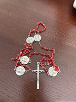 Entire rosary laid out showing red beads, crucifix, and medals