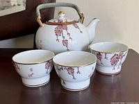 Teapot with three of four cups showing overall design and handle