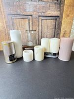 Group view of all seven pillar candles, glass lantern behind, floating candle inside