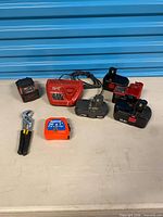 Group shot of all batteries, charger, tape measure and pliers on table