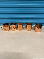 Front view of all five copper Moscow Mule mugs lined up