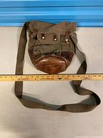 Full view of canvas and leather shoulder bag with ruler for scale