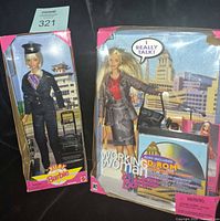 Front view of both boxed dolls showing outfits and accessories