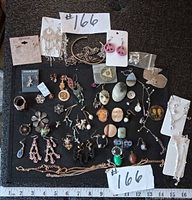 Overall lot showing quantity and variety of jewelry pieces on black background