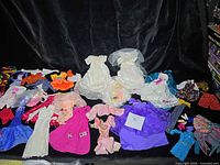 Overall lot with multiple gowns, separates, accessories and shoes displayed on black backdrop