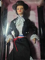 Close view of doll inside box showing outfit, hat, cane and lace details