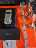 Top view of Porsche paperweight in box alongside three cat figurines and ruler