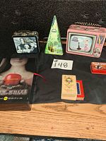Group shot of all items showing three lunchbox tins, wind chime, Snow White box, playing cards