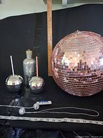 Full lot showing pink disco ball, two tumblers, decanter cover, ruler, and necklaces