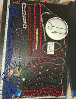 Overview of all bead necklaces and pendants on board with ruler for scale