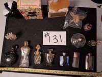 Overall lot showing approximately 15 assorted perfume bottles and boxes on black mat with ruler for scale