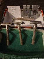 Three safety razors front view with blade dispensers and metal case