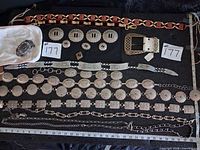Overall view of six belts, two buckles, loose conchos and measuring scale