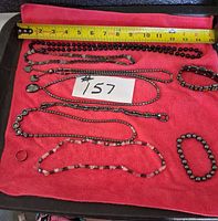 Overview of all nine hematite-style pieces on cloth with measuring tape