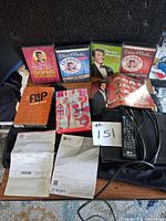 Overview of all items on table: LG DVD player, remote, manuals, Dean Martin DVDs, Flip Wilson Show set, Laugh-In DVD, Time Life paperwork